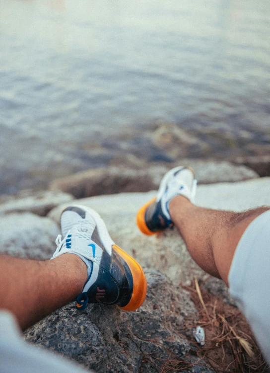 the legs of a person wearing sports shoes near water