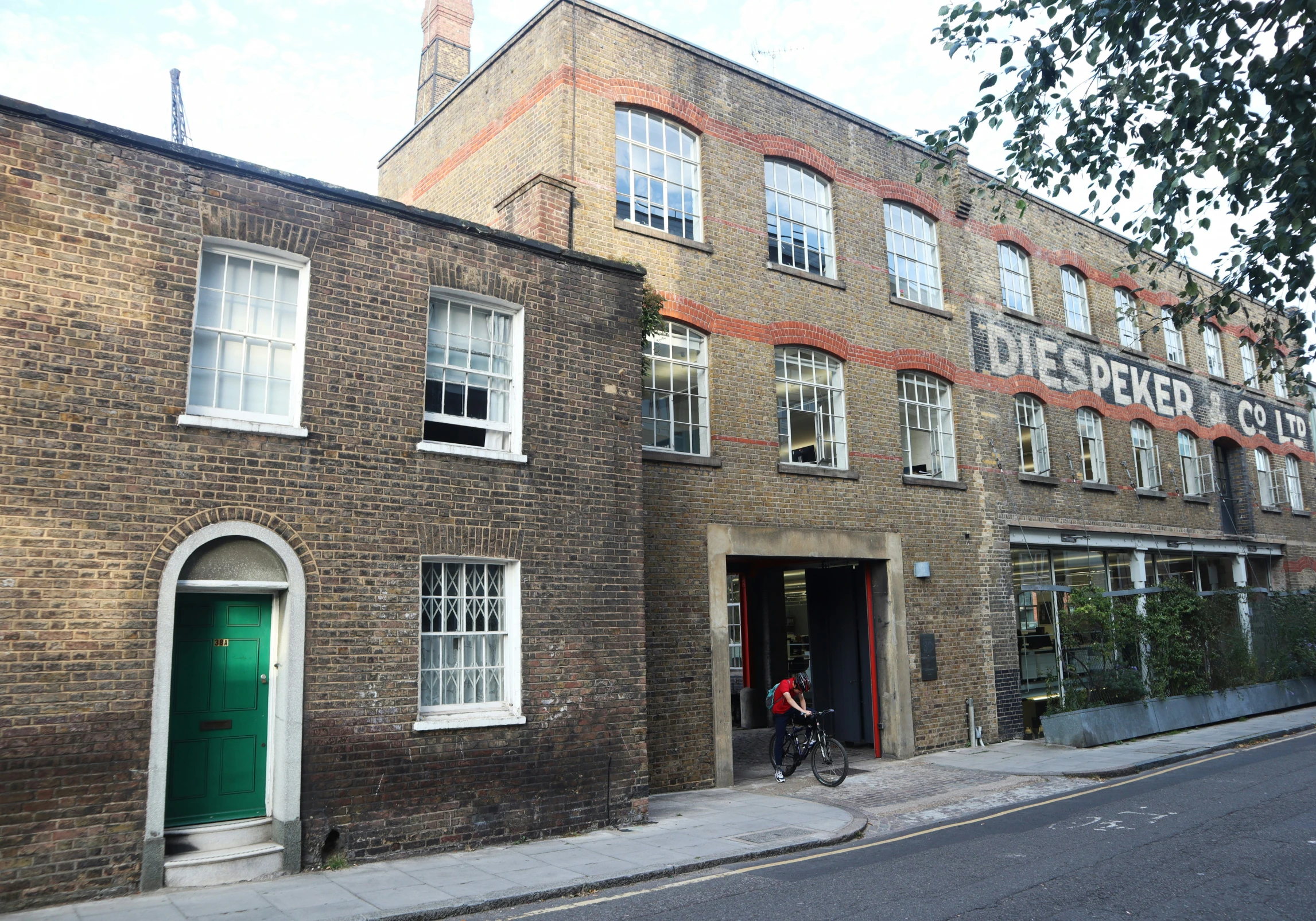 a brick building with a green door and bicycle in front