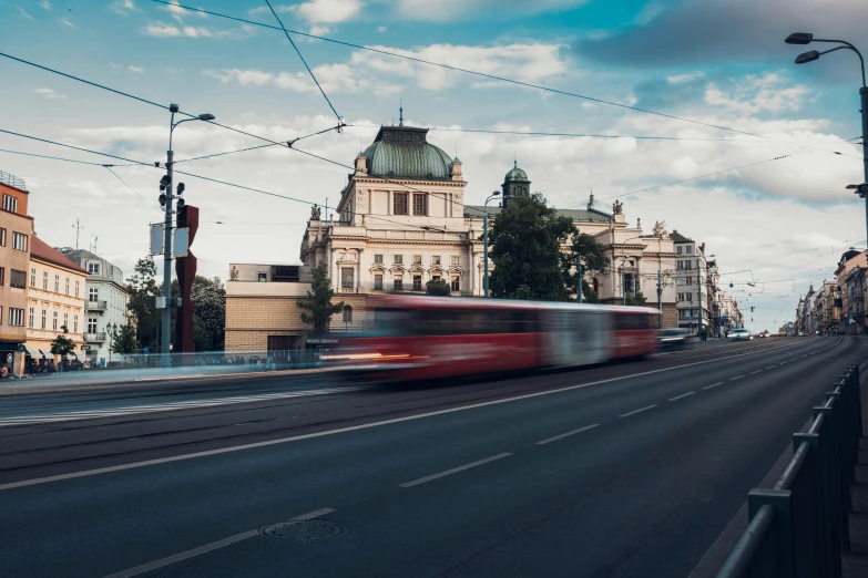 a red train is traveling down a city street