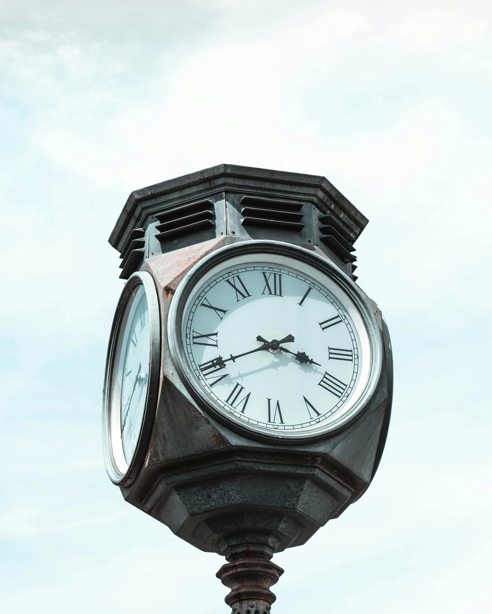 a pole with a clock on top with sky in background