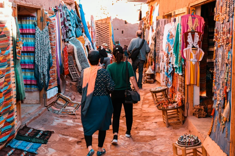 two women are walking through a small market