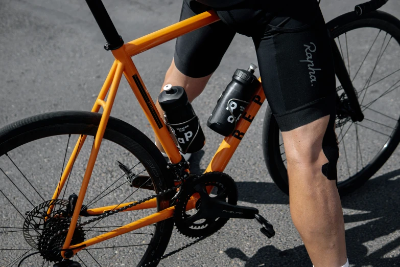 the feet of a person riding an orange bicycle