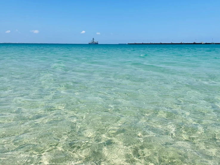 a sail boat is in the distance over clear blue water