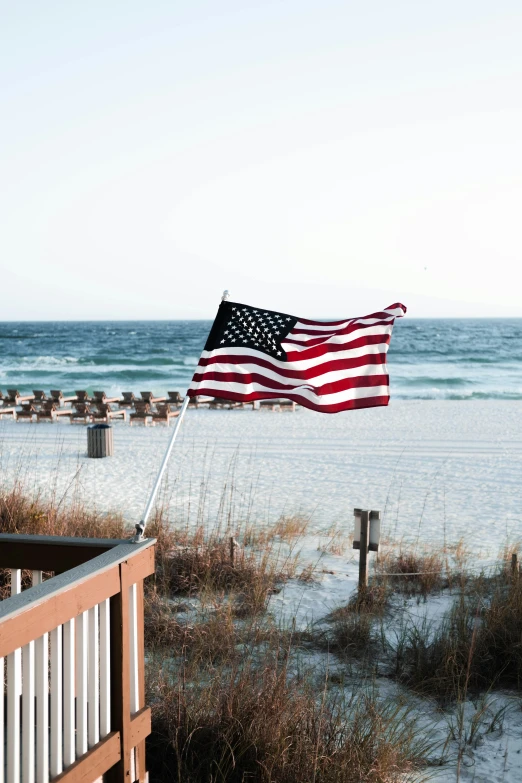 a flag is standing on the beach next to the water