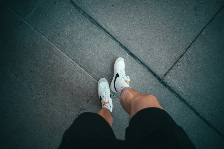 the feet of a person wearing white shoes on a street