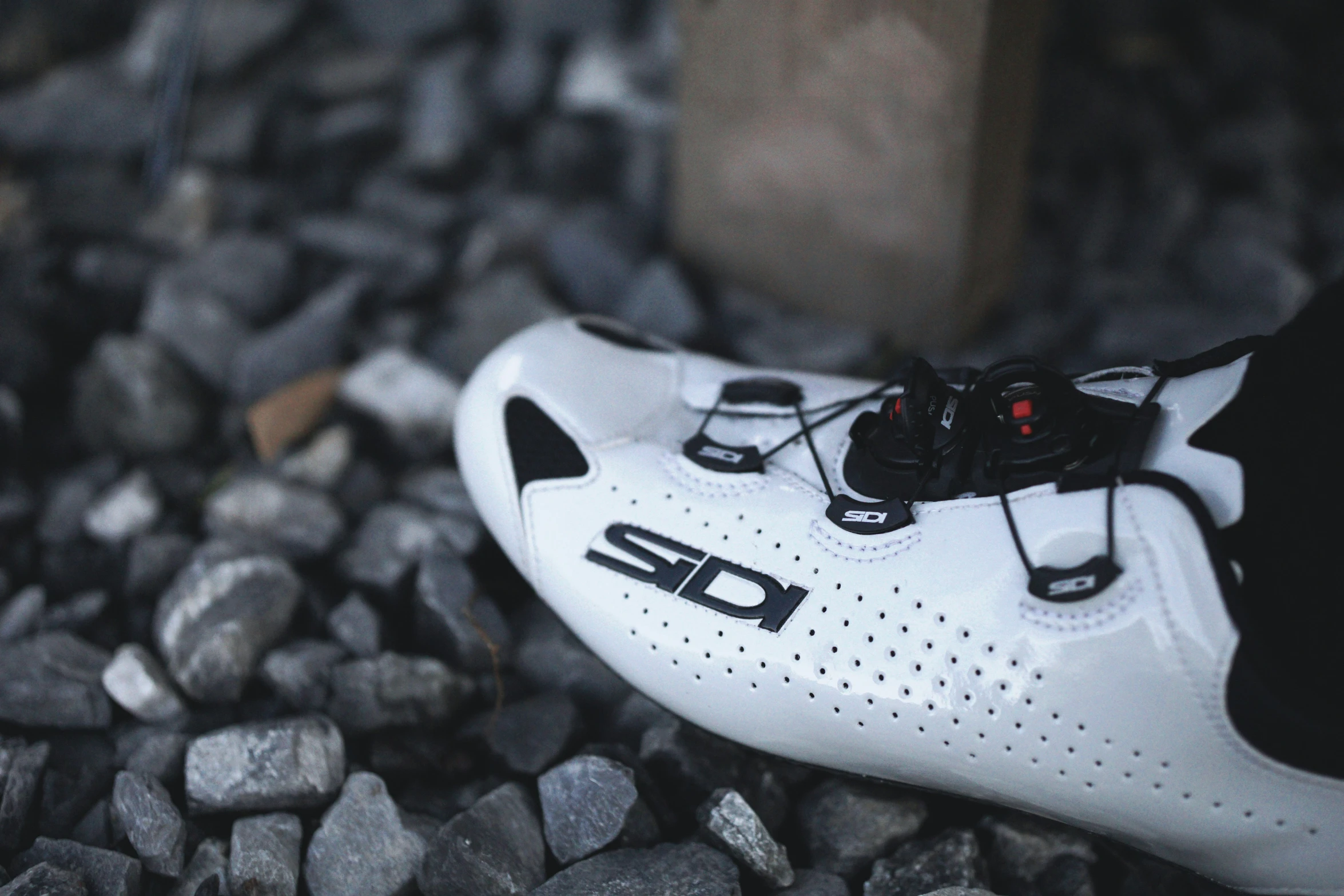 close up of black and white shoes on some gravel