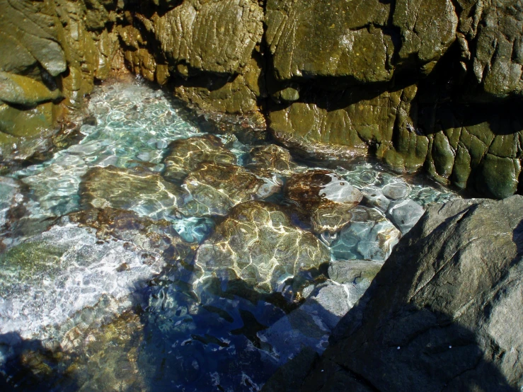 clear blue water surrounded by rocks on the coast