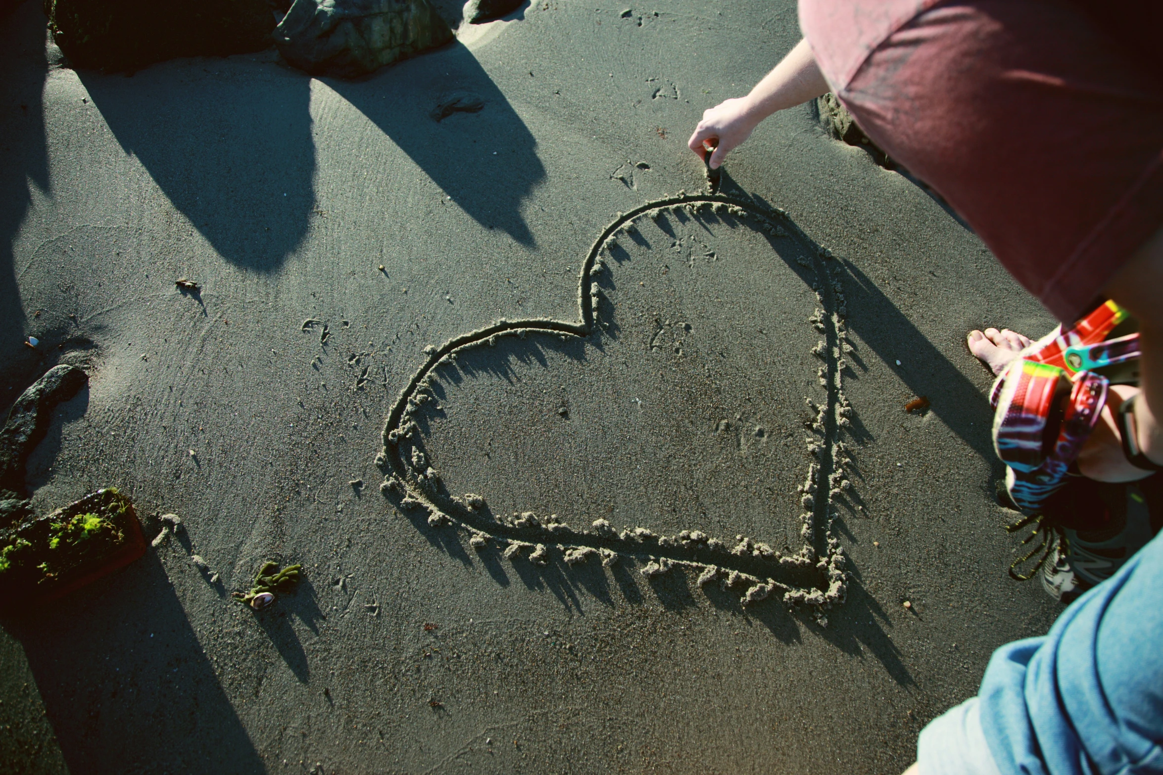 two children draw a heart in the sand