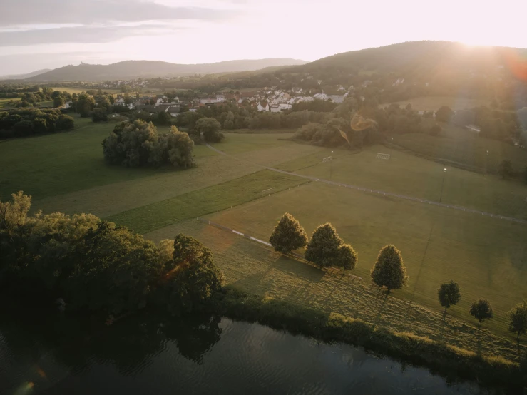 the sun sets over a small village on a hillside above a lake