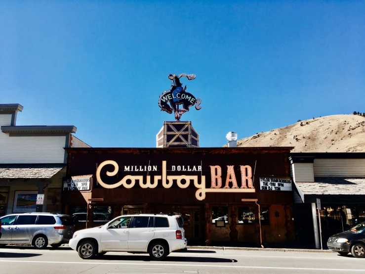 the outside of a cowboy bar with some cars outside