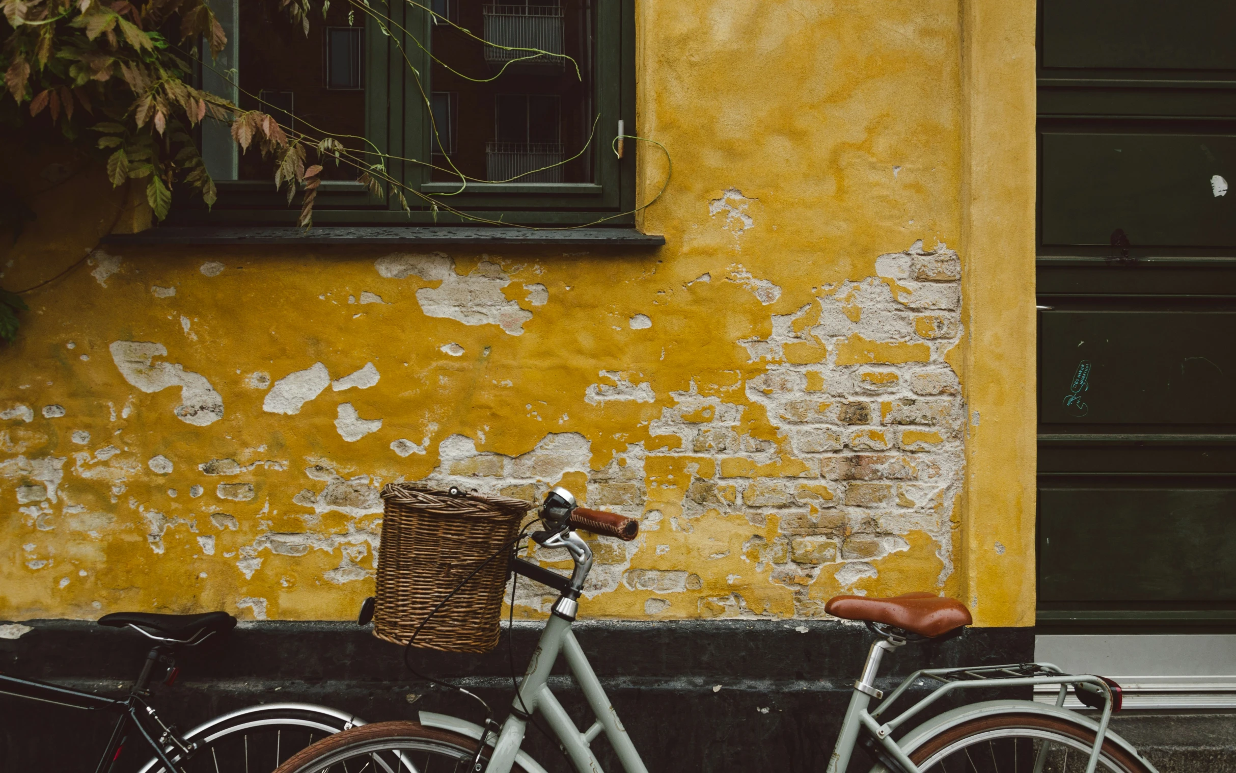 an old grey bicycle parked next to a yellow building