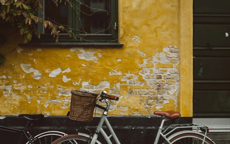 an old grey bicycle parked next to a yellow building