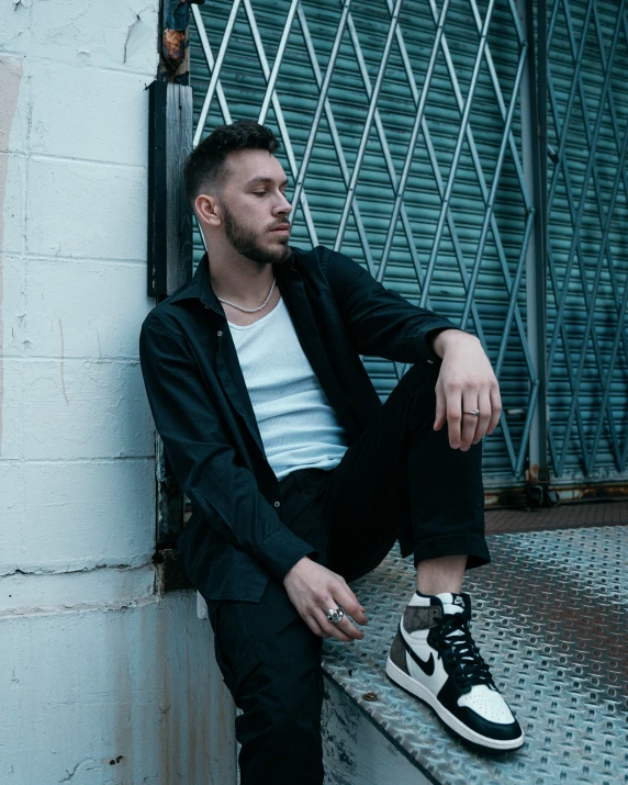 a man is sitting on a ledge with his feet crossed