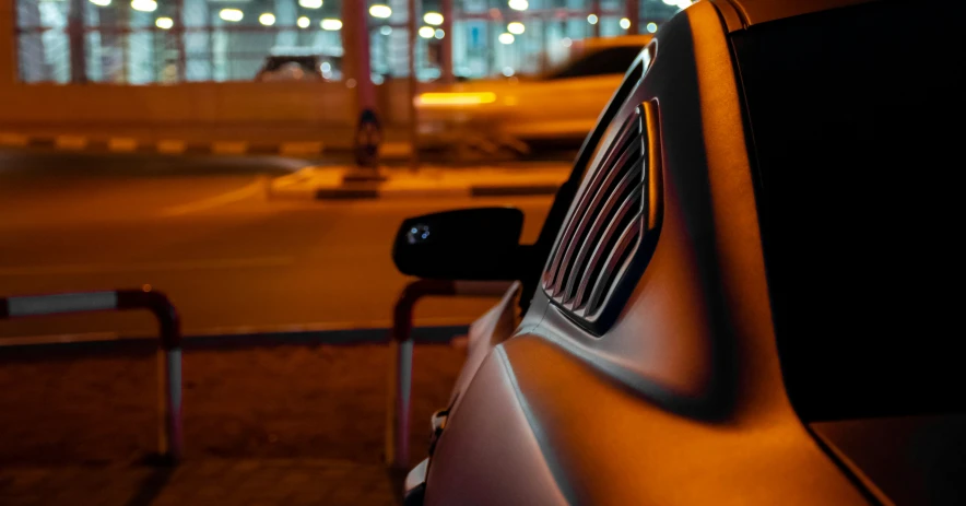 closeup of front view mirror in a car with cars parked on the street behind