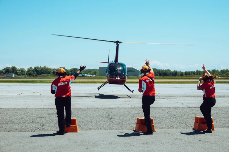 three employees stand on the tarmac with their arms in the air