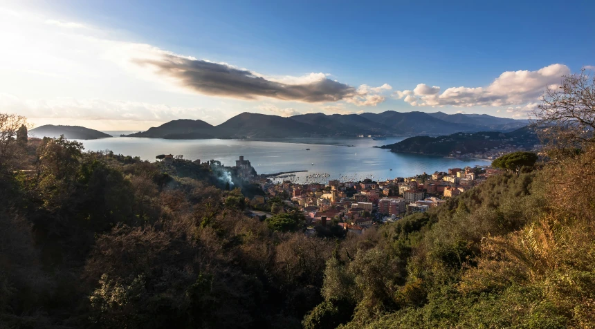 a city next to the ocean on a lush green hillside