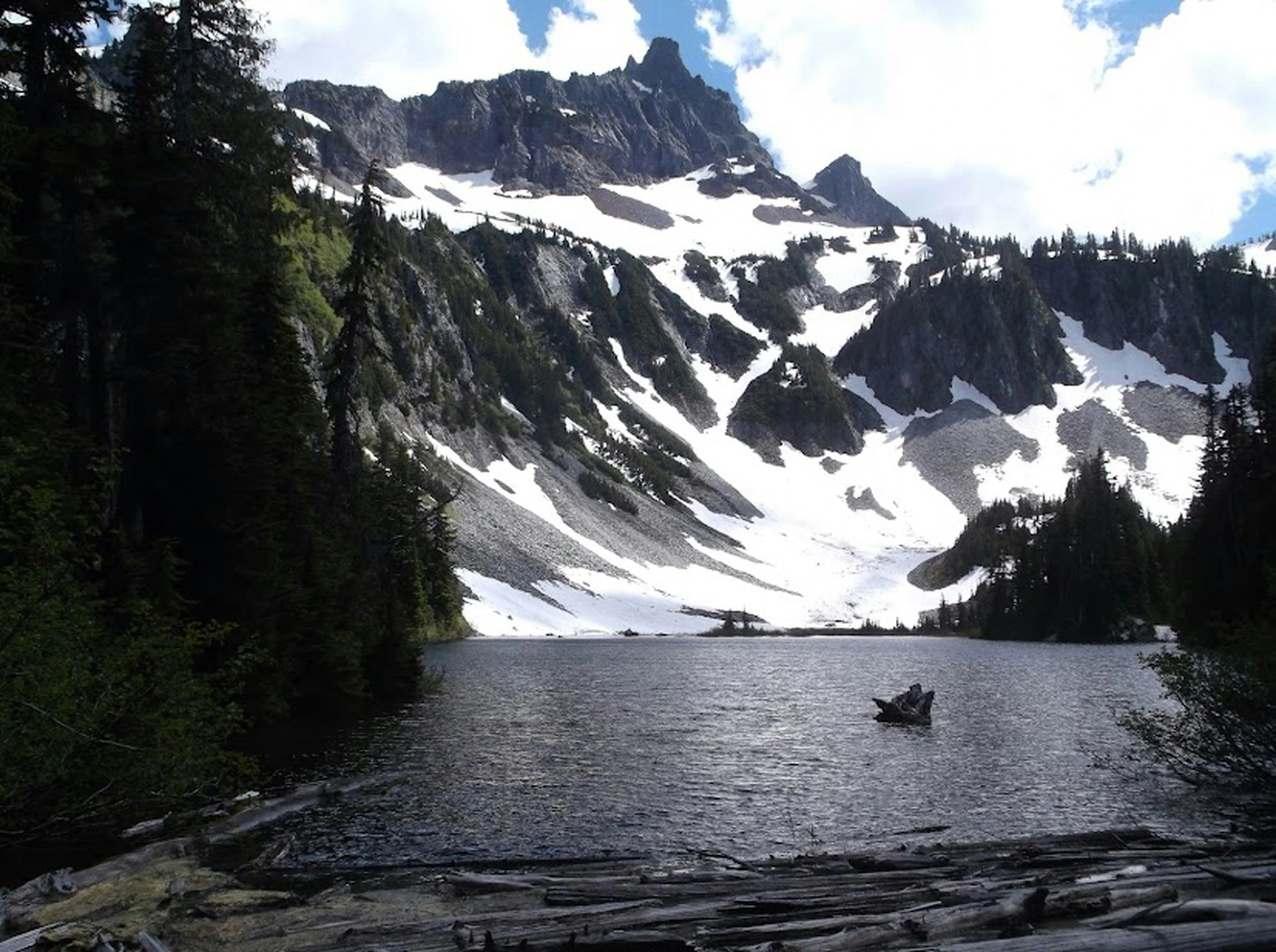 a lone boat in the lake with large snow covered mountain behind