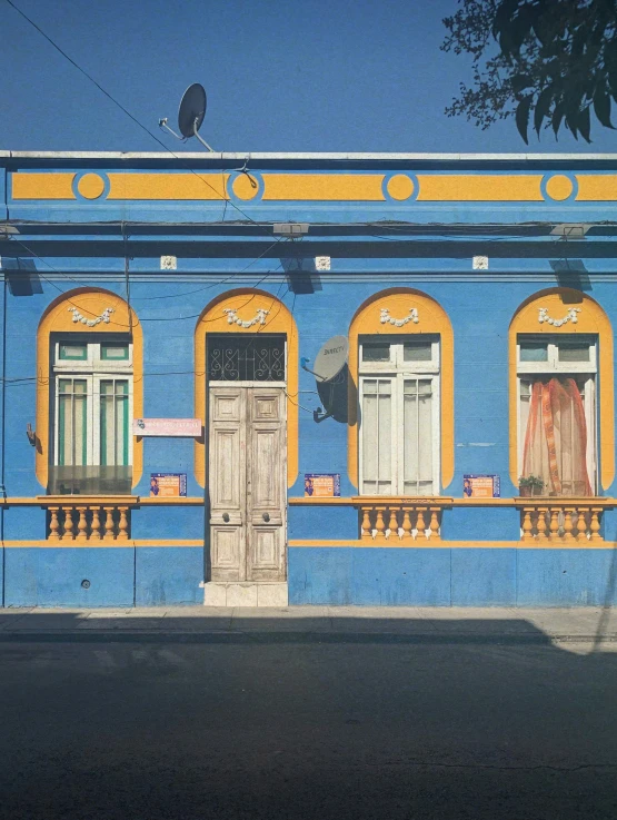 a blue and yellow building has three windows