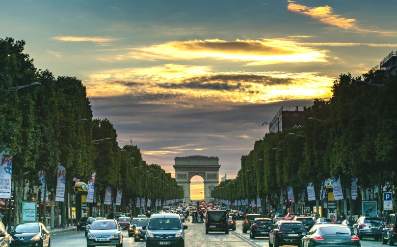 the city street has cars parked on both sides and in front of the monument