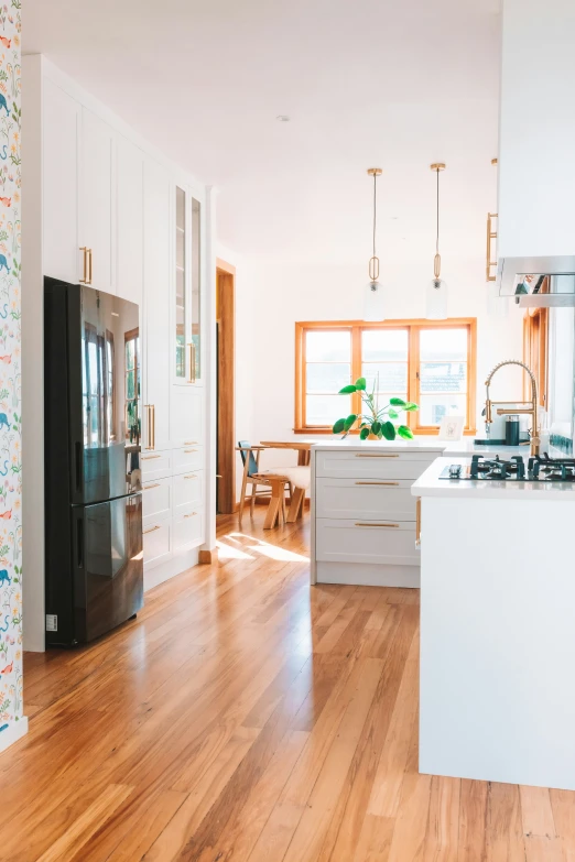 an empty kitchen with wooden floors and white cabinetry