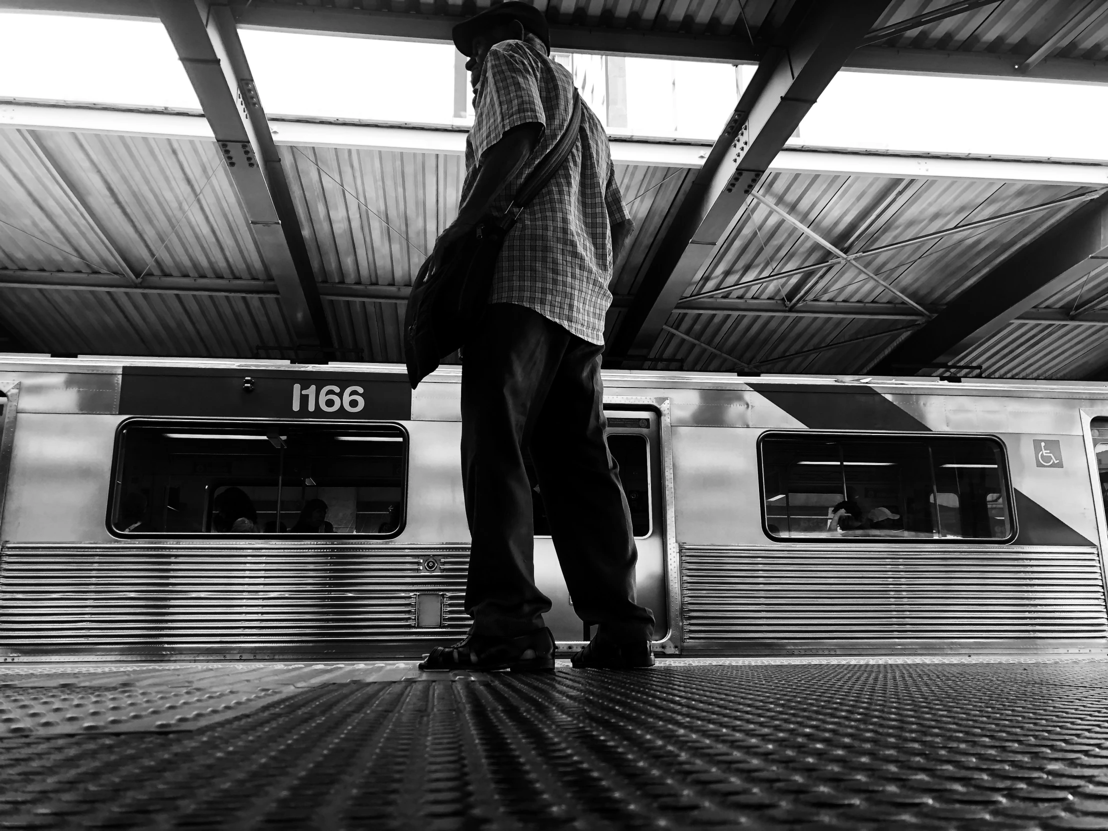 black and white pograph of person standing at train station