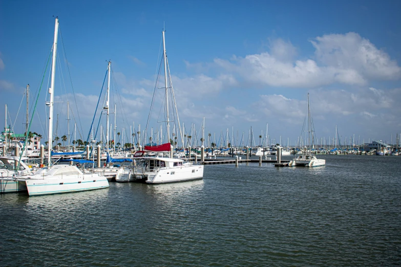 several sail boats in the water near a pier