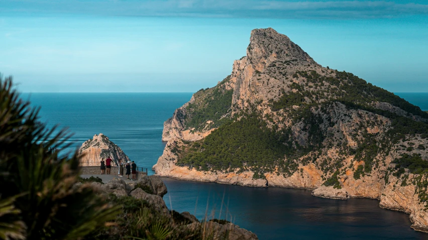 a person is taking a pograph while on a large rock near a body of water