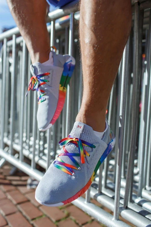 a person wearing grey sneakers on top of a metal fence