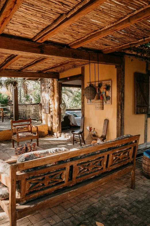 the outside of a home with wooden benches and chairs