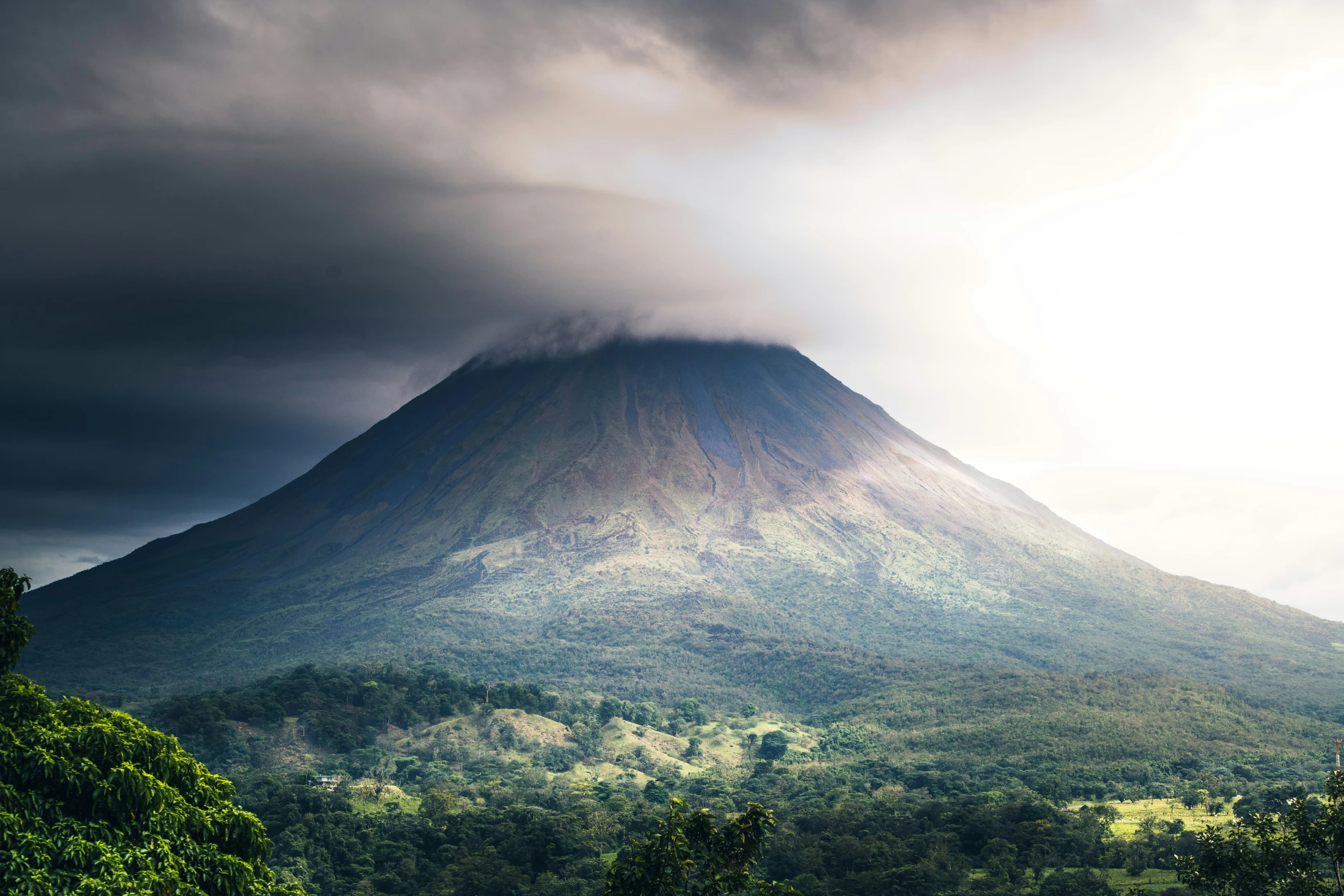 the clouds are hovering over the mountain on a cloudy day