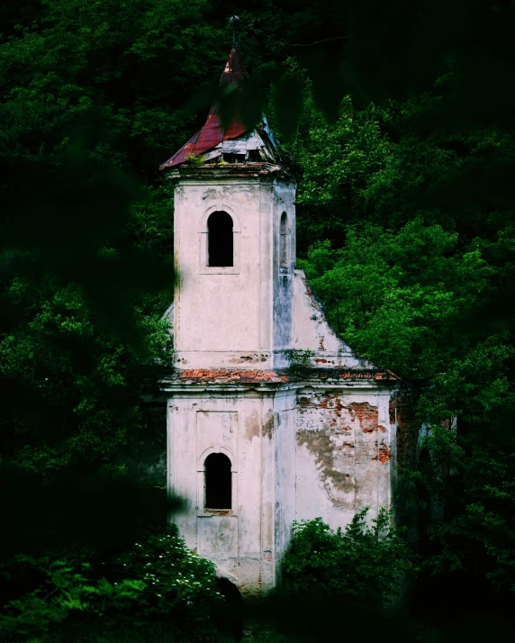 an old church tower in the woods with trees surrounding