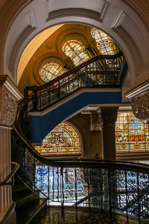 the view looking down a stairway at some stained glass windows