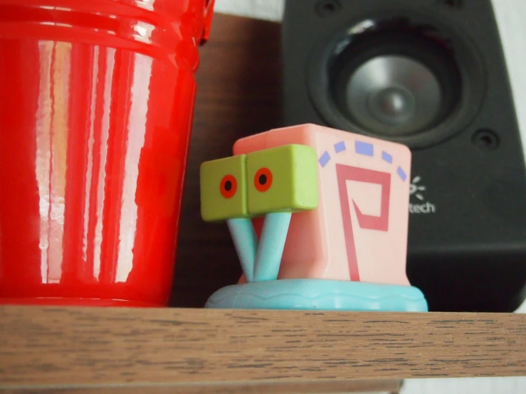 a toy and speaker on top of a shelf