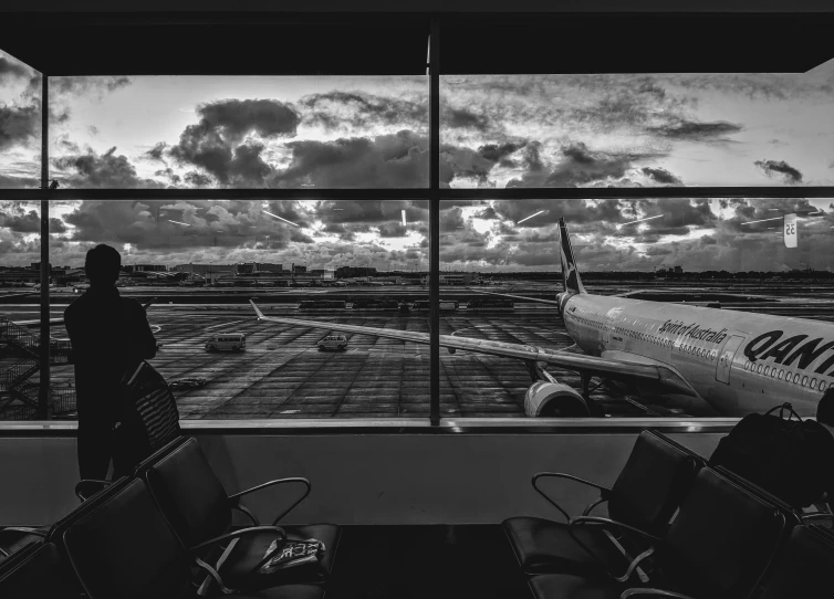 black and white image of people standing in front of an airport window