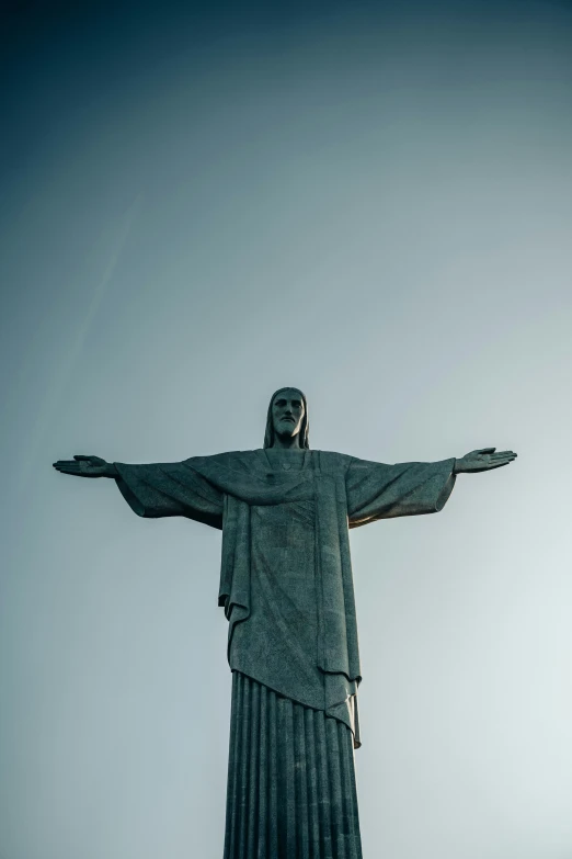 the statue is standing in the air, and has its arms wide open