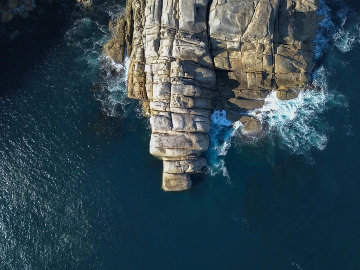 a bird's eye view of a rocky beach with crashing waves