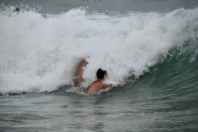 a woman in the ocean on her stomach laying on a surf board