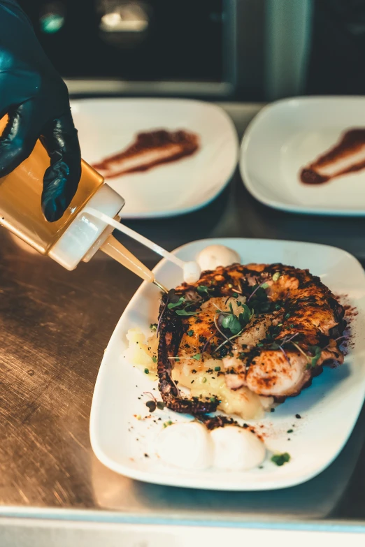 someone pouring sauce onto a plate with food on it