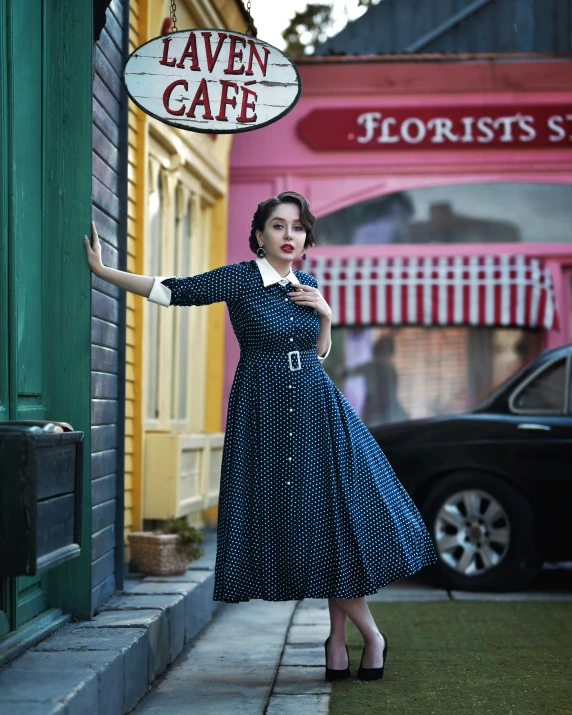 a woman in a dress holding a sign next to a building