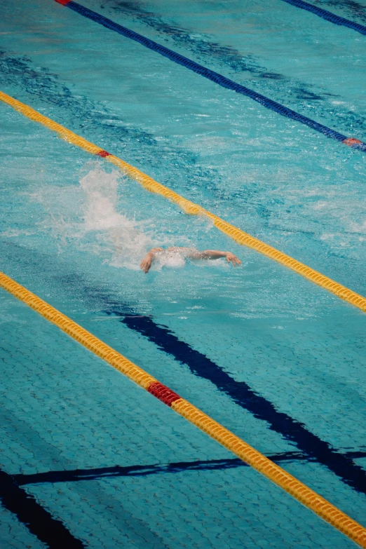 a swimmers swimming in an empty pool with a red ball