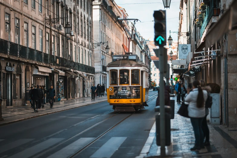 there is a yellow trolley that is on the street