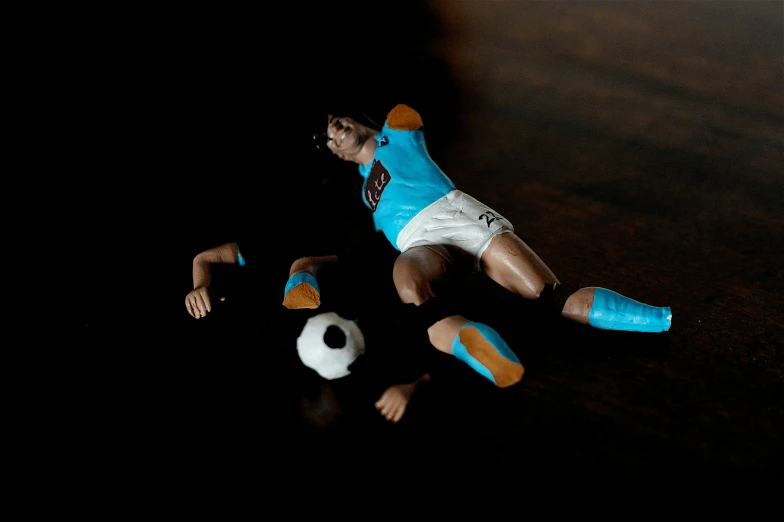 a toy soccer player has fallen over and the ball is upside down