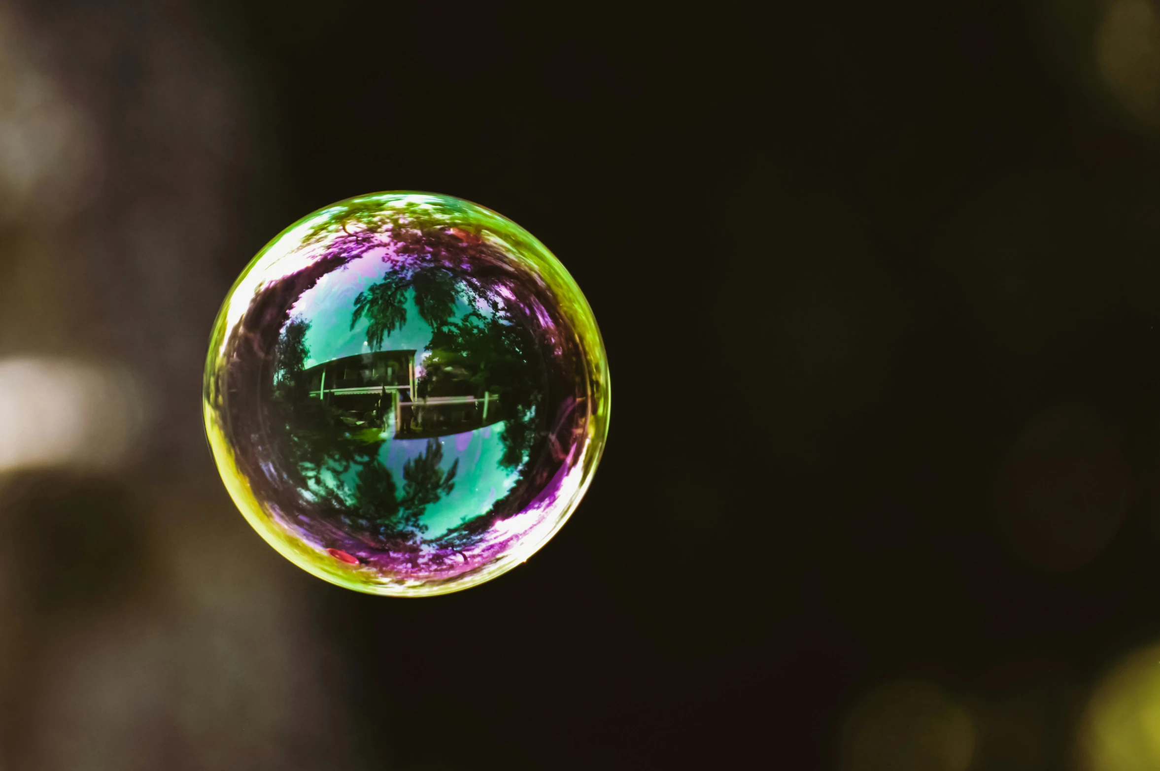 a glass ball is being released with reflections of a building and trees