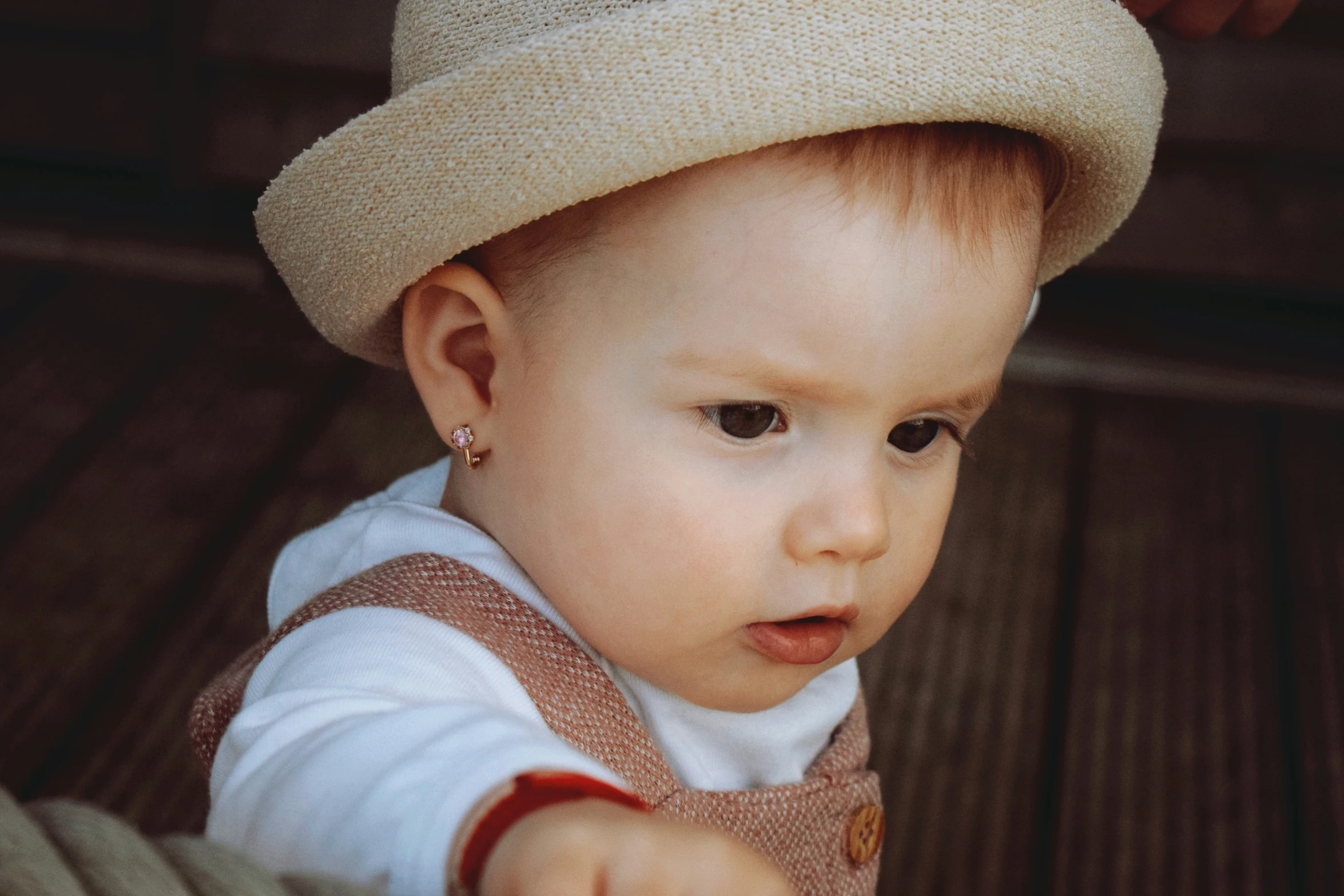 a small child wearing a tan hat looking at the camera