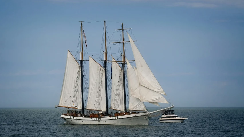 large white boat sailing across the ocean with a smaller one behind it