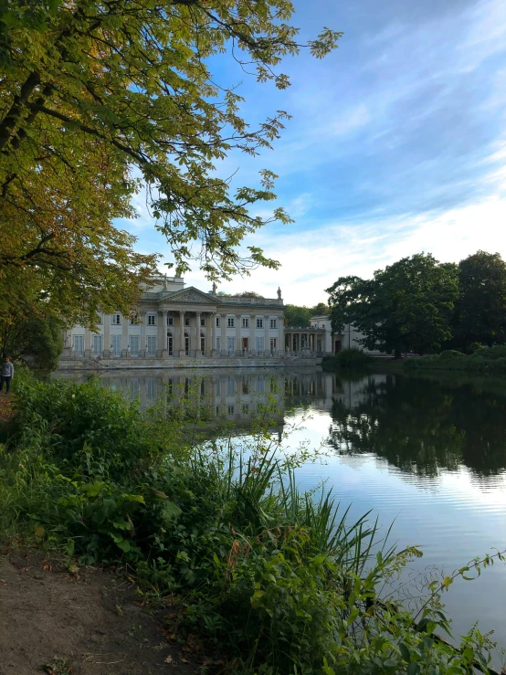 a mansion sitting next to a lake in a park