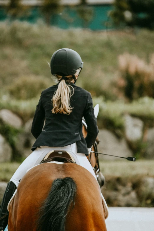 a woman riding on the back of a brown horse