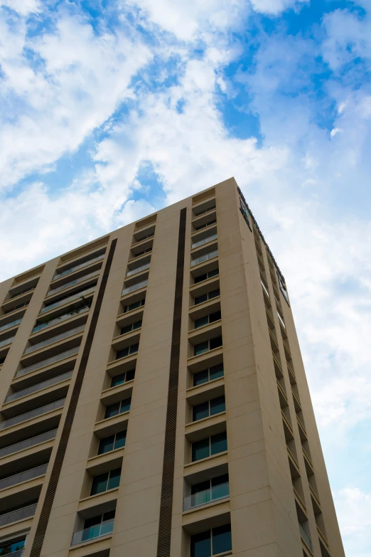 the large building has windows under a cloudy blue sky