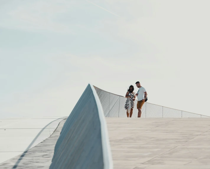 two people are standing on a railing in the middle of a cement area