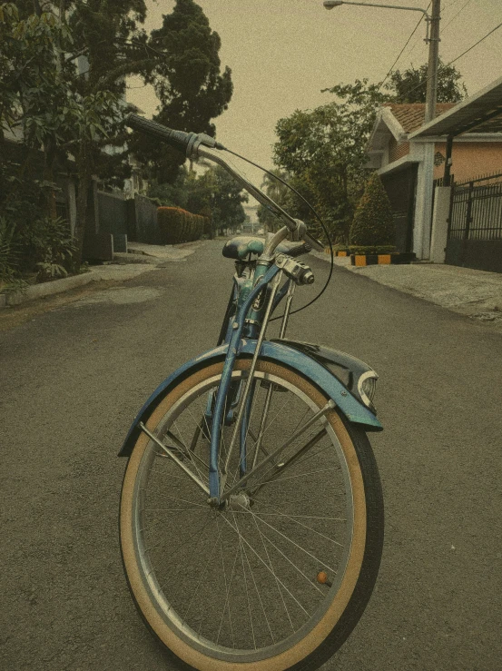 an old blue bicycle parked at the end of the street